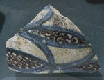 Frammento di boccale in maiolica bianca con disegni curvilinei azzurri e grani neri